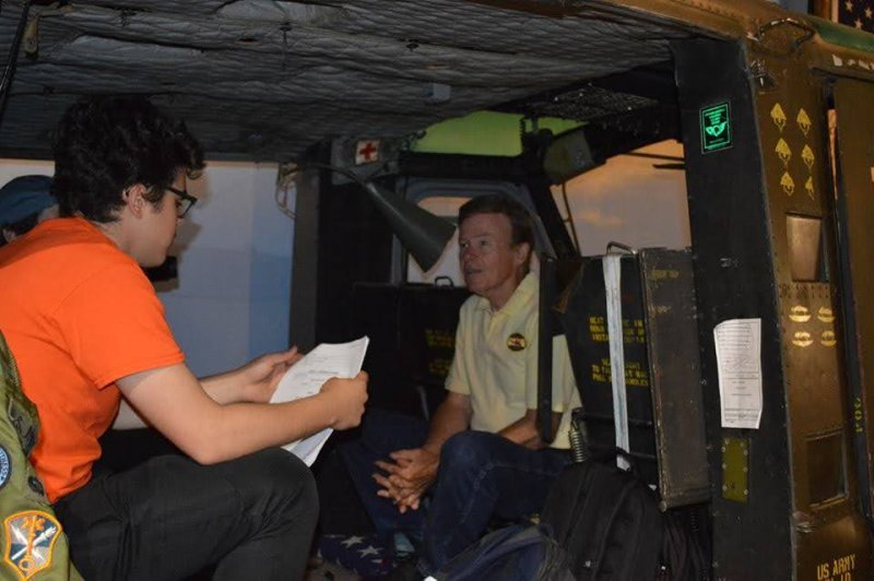 Veteran and museum founder Craig LaMountain fields questions from a student inside a helicopter that is obviously not moving, one holds a paper