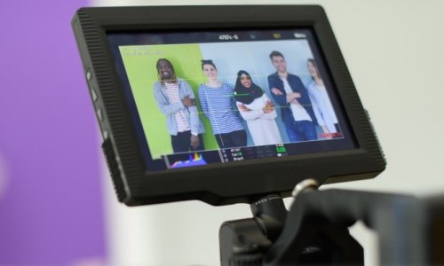 photo of a viewer on a video camera looking at 5 people being filmed