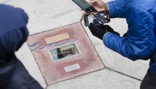 A sidewalk embedded historical marker for Paul Hardwick, a Black man & victim of the 1919 Tulsa Race Massacre in OK. Victim beside a burnt building.